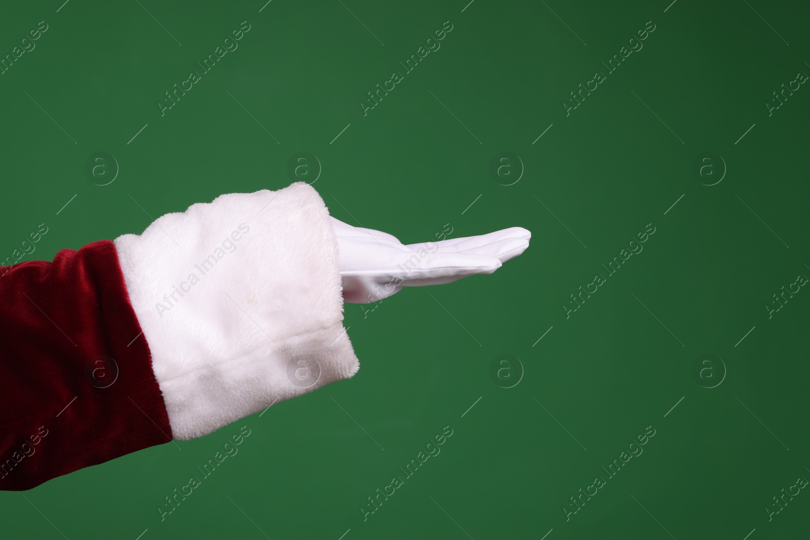 Photo of Santa Claus holding something on green background, closeup. Space for text