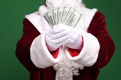 Photo of Santa Claus with dollar banknotes on green background, closeup