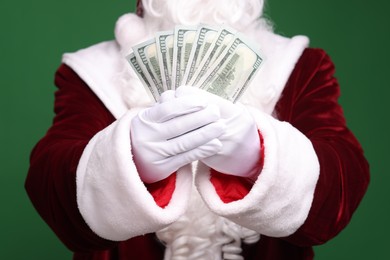 Photo of Santa Claus with dollar banknotes on green background, closeup