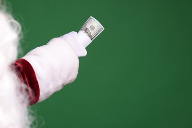 Photo of Santa Claus with dollar banknotes on green background, closeup. Space for text