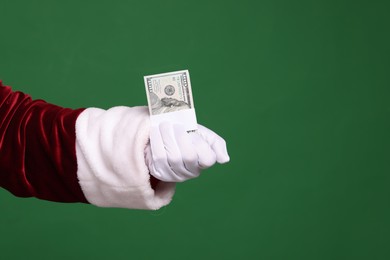 Photo of Santa Claus with dollar banknotes on green background, closeup. Space for text