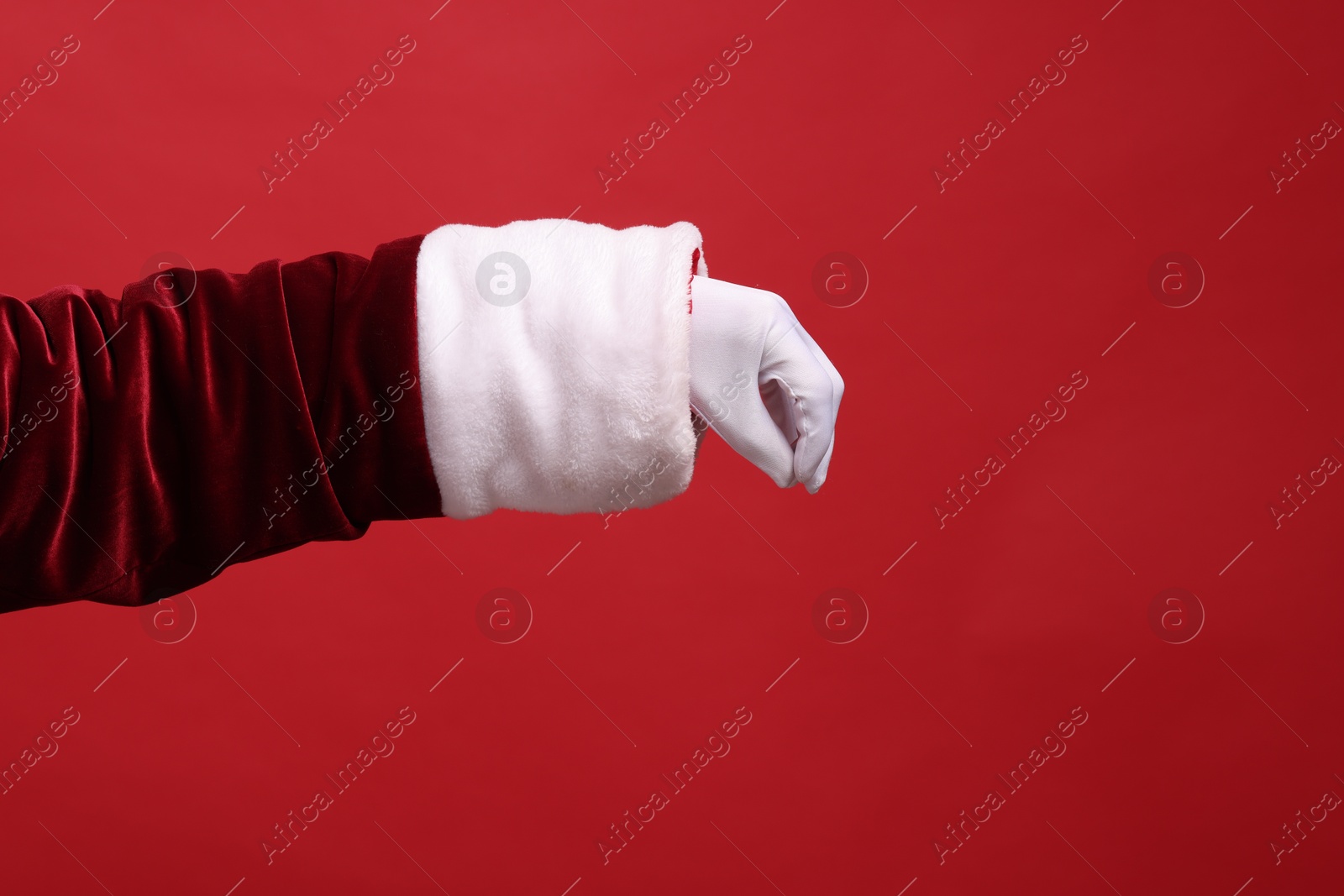 Photo of Santa Claus holding something on red background, closeup. Space for text