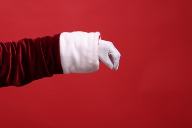 Photo of Santa Claus holding something on red background, closeup. Space for text