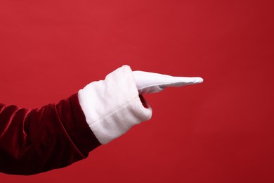 Photo of Santa Claus holding something on red background, closeup