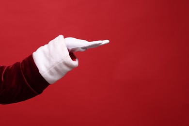 Photo of Santa Claus holding something on red background, closeup. Space for text