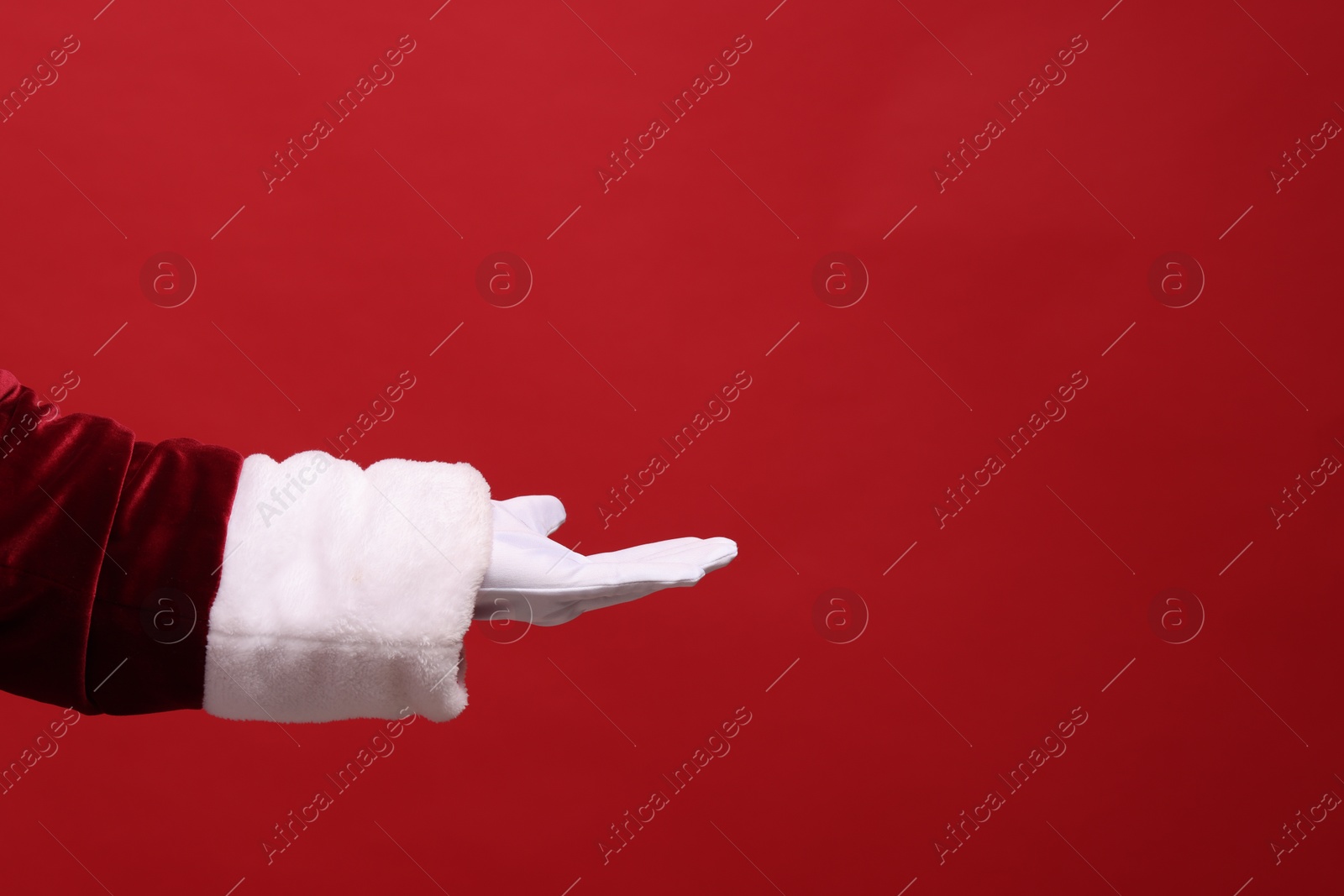 Photo of Santa Claus holding something on red background, closeup. Space for text