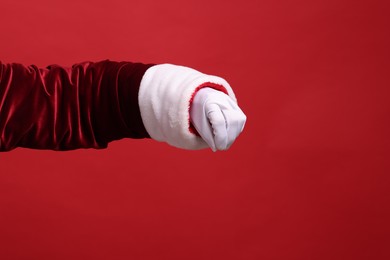 Photo of Santa Claus holding something on red background, closeup. Space for text