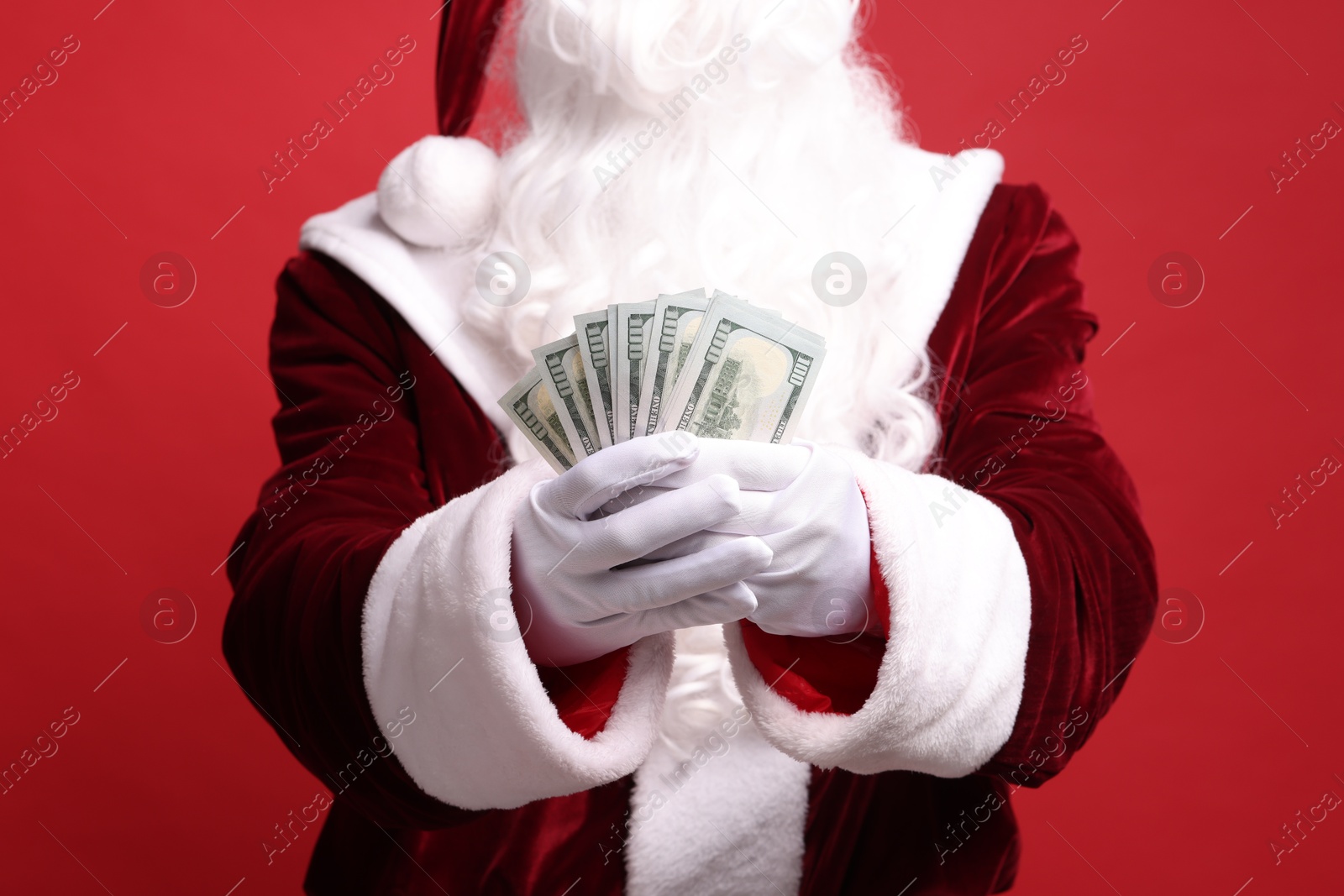 Photo of Santa Claus with dollar banknotes on red background, closeup