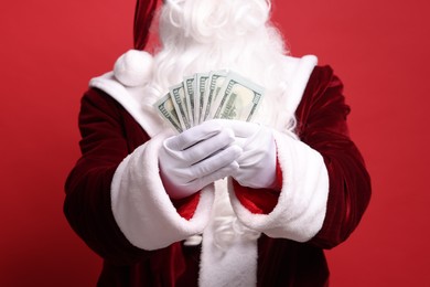 Photo of Santa Claus with dollar banknotes on red background, closeup