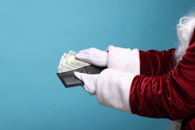 Photo of Santa Claus with dollar banknotes on light blue background, closeup