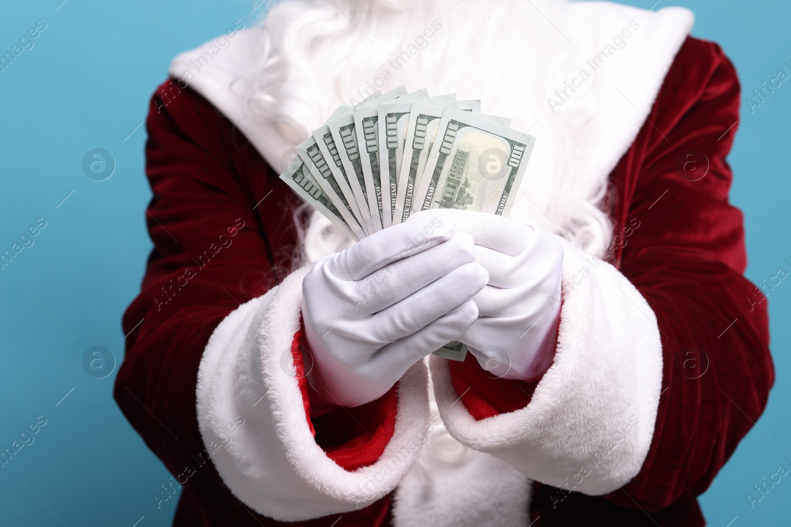 Photo of Santa Claus with dollar banknotes on light blue background, closeup