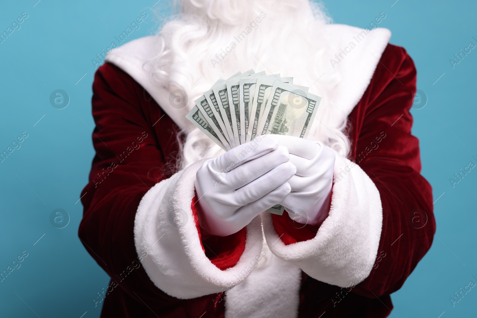 Photo of Santa Claus with dollar banknotes on light blue background, closeup