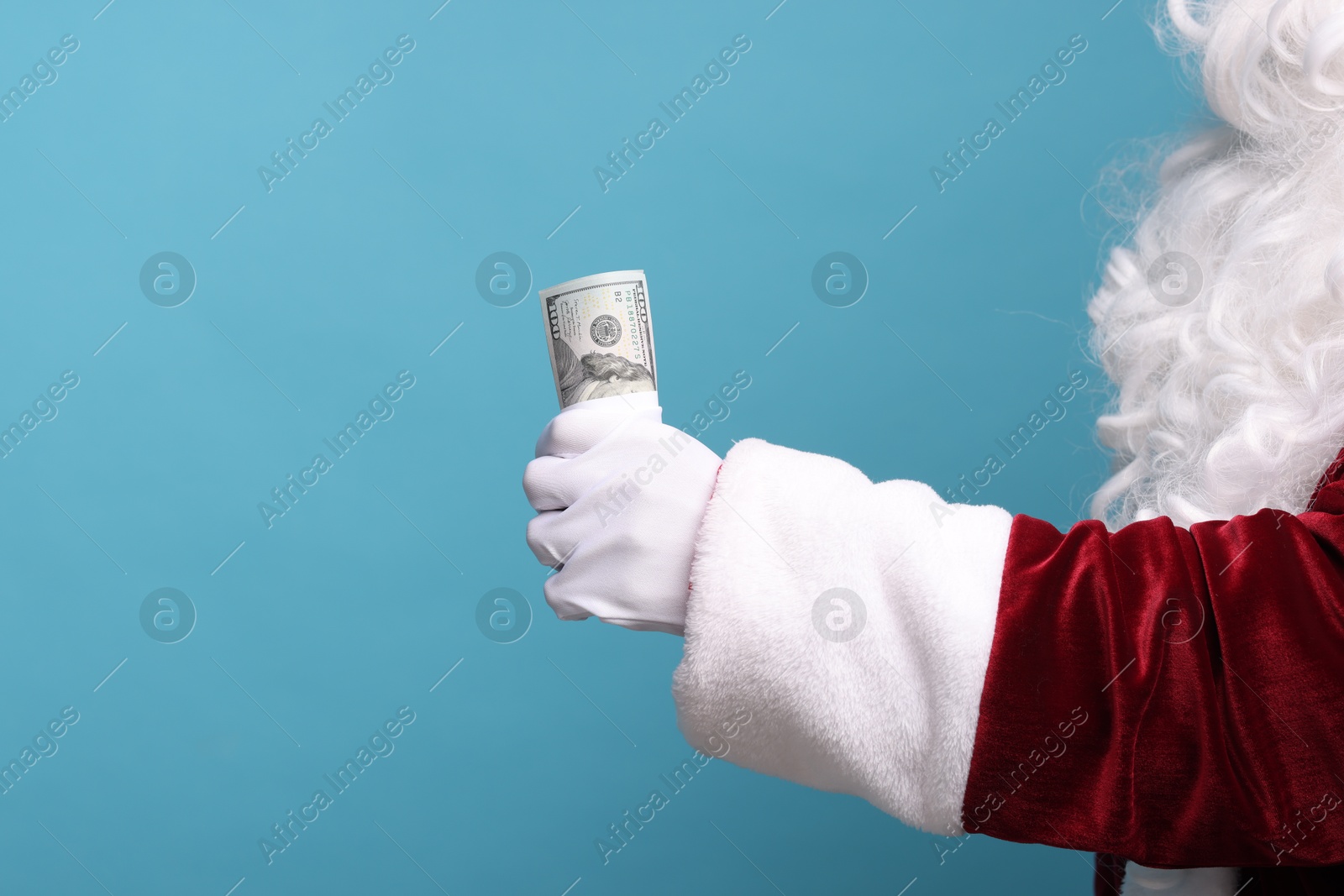 Photo of Santa Claus with dollar banknotes on light blue background, closeup. Space for text