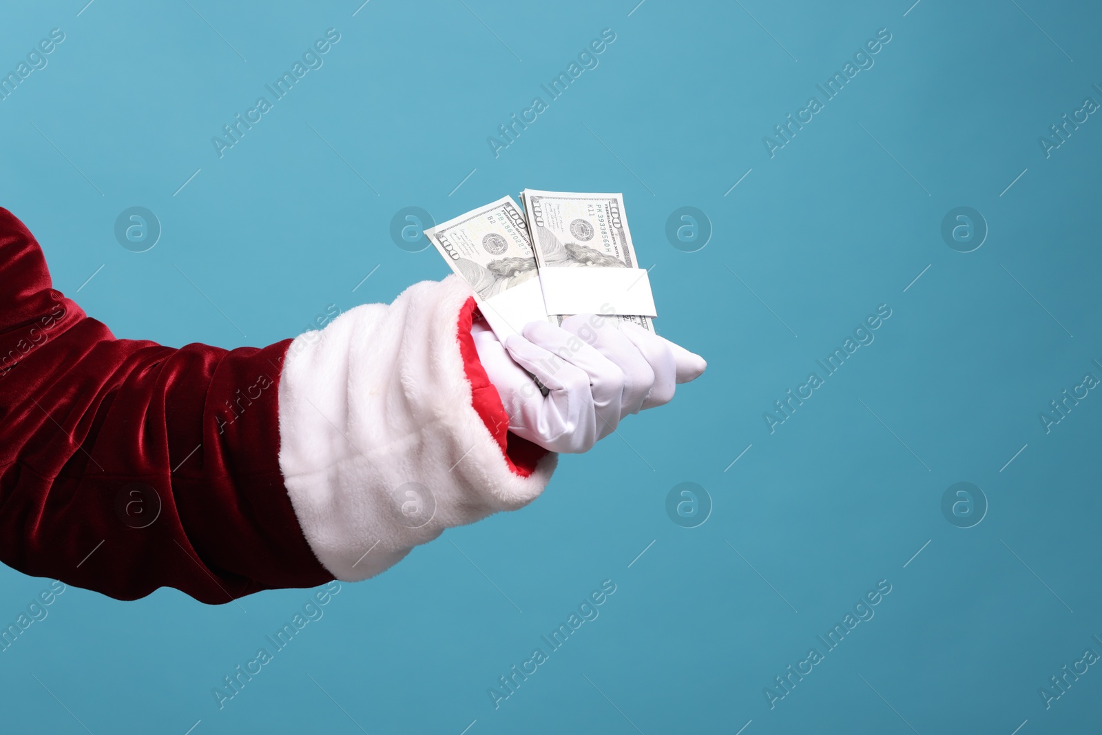 Photo of Santa Claus with dollar banknotes on light blue background, closeup. Space for text