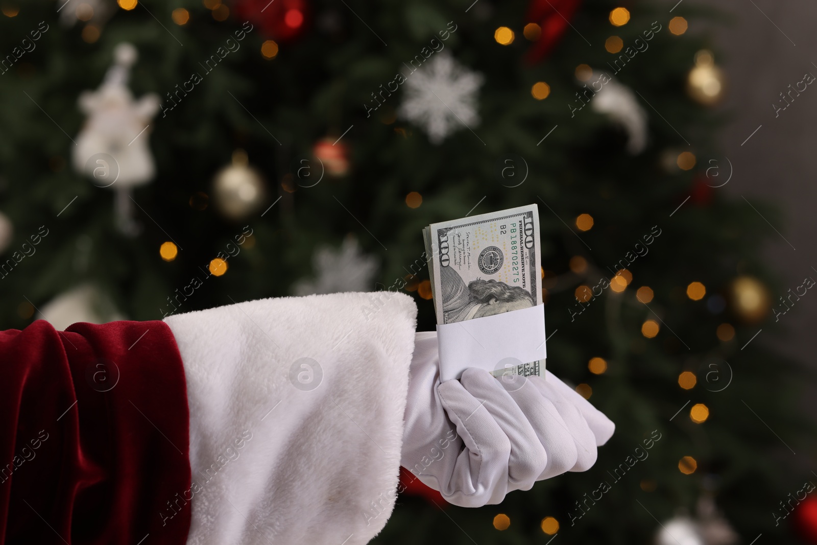 Photo of Santa Claus with dollar banknotes near Christmas tree indoors, closeup