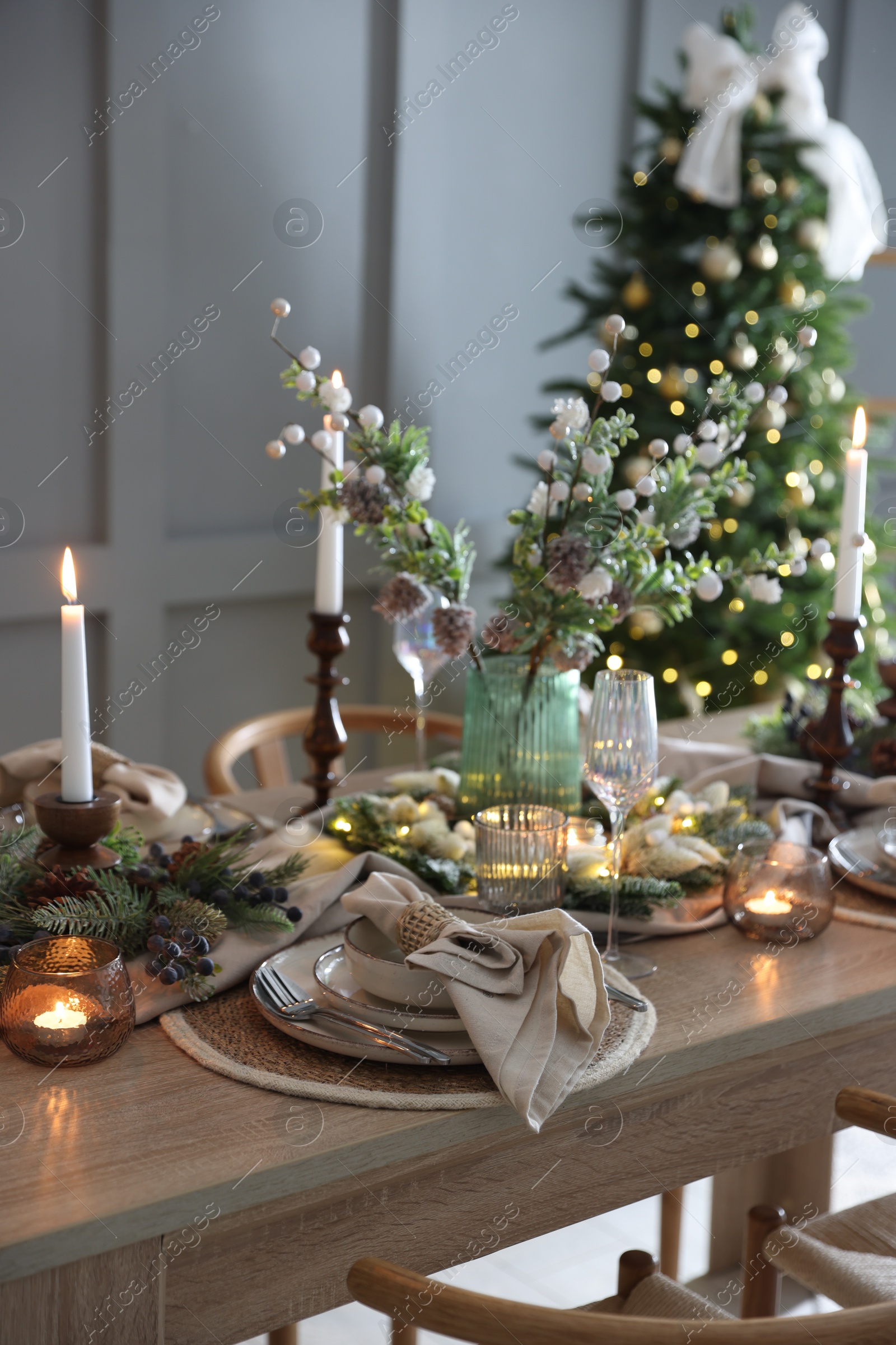 Photo of Christmas celebration. Festive table setting with dishware, glasses and decor in room