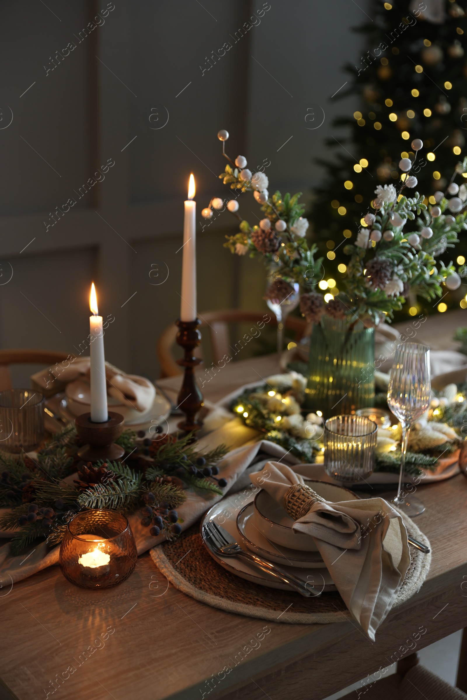 Photo of Christmas place setting with festive decor on wooden table in room