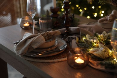 Photo of Christmas place setting with festive decor on wooden table in room