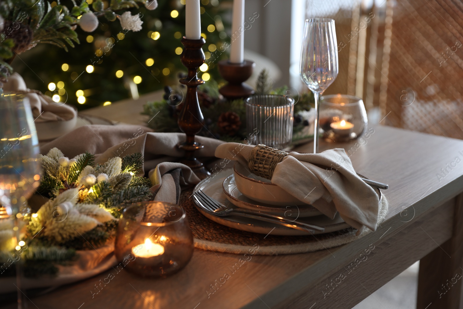 Photo of Christmas place setting with festive decor on wooden table in room