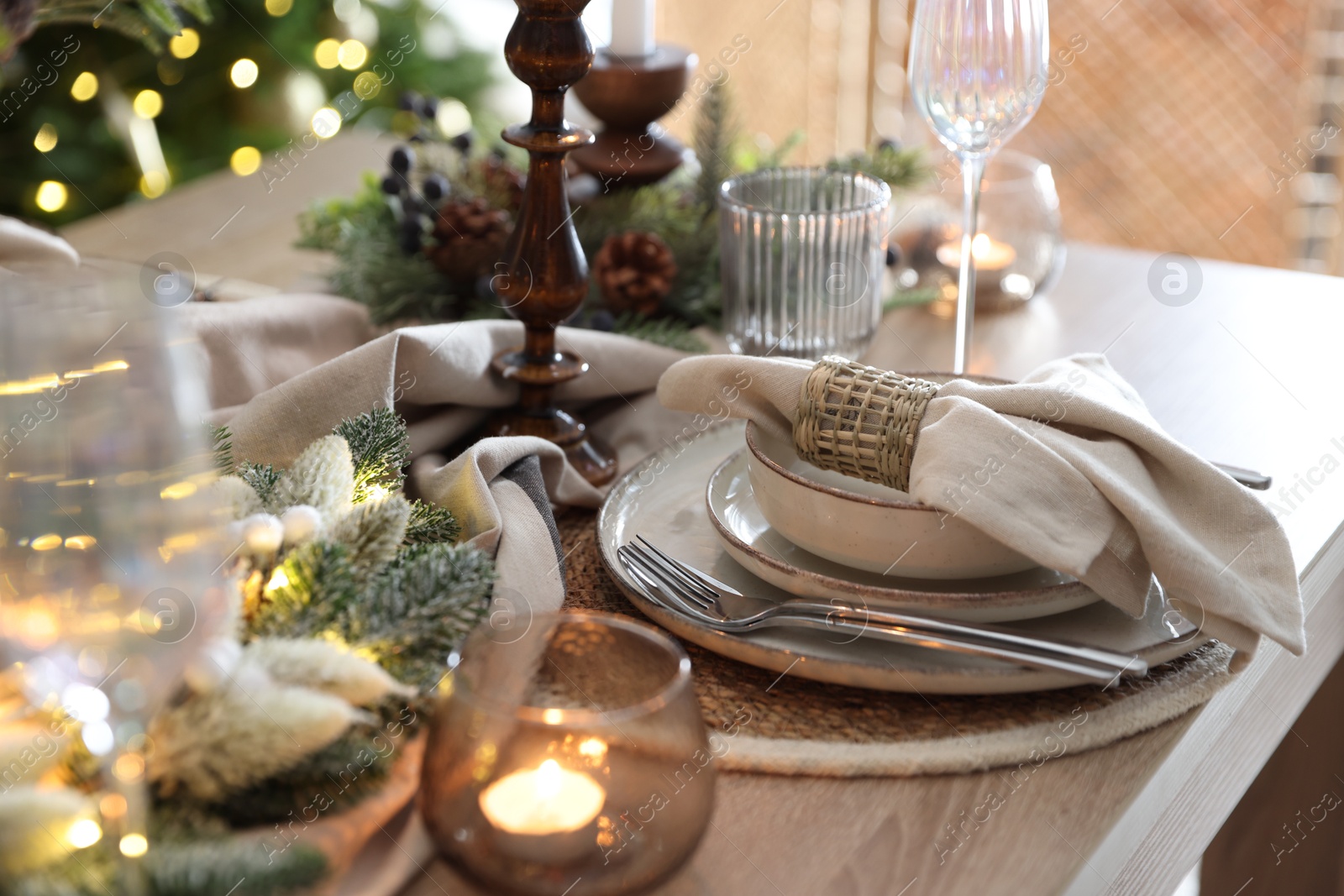 Photo of Christmas place setting with festive decor on wooden table in room, closeup