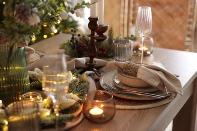 Photo of Christmas place setting with festive decor on wooden table in room