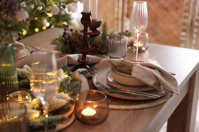 Photo of Christmas place setting with festive decor on wooden table in room