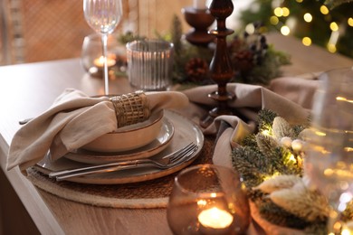 Photo of Christmas place setting with festive decor on wooden table in room, closeup