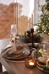 Photo of Christmas place setting with festive decor on wooden table in room