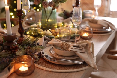 Photo of Christmas place setting with festive decor on wooden table in room