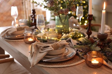 Photo of Christmas place setting with festive decor on wooden table in room