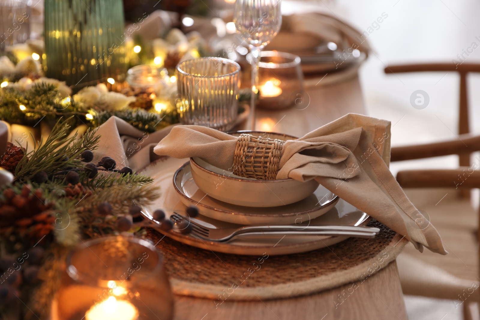 Photo of Christmas place setting with festive decor on wooden table in room, closeup