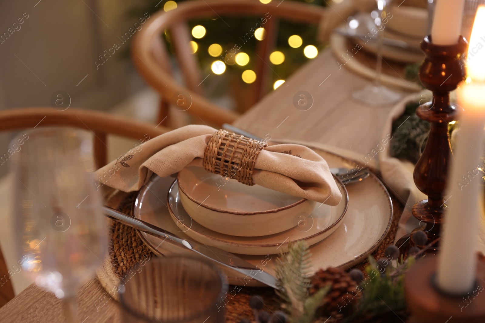 Photo of Christmas place setting with festive decor on wooden table in room, closeup