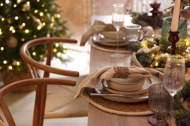 Photo of Christmas place setting with festive decor on wooden table in room