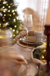 Photo of Christmas place setting with festive decor on wooden table in room, closeup