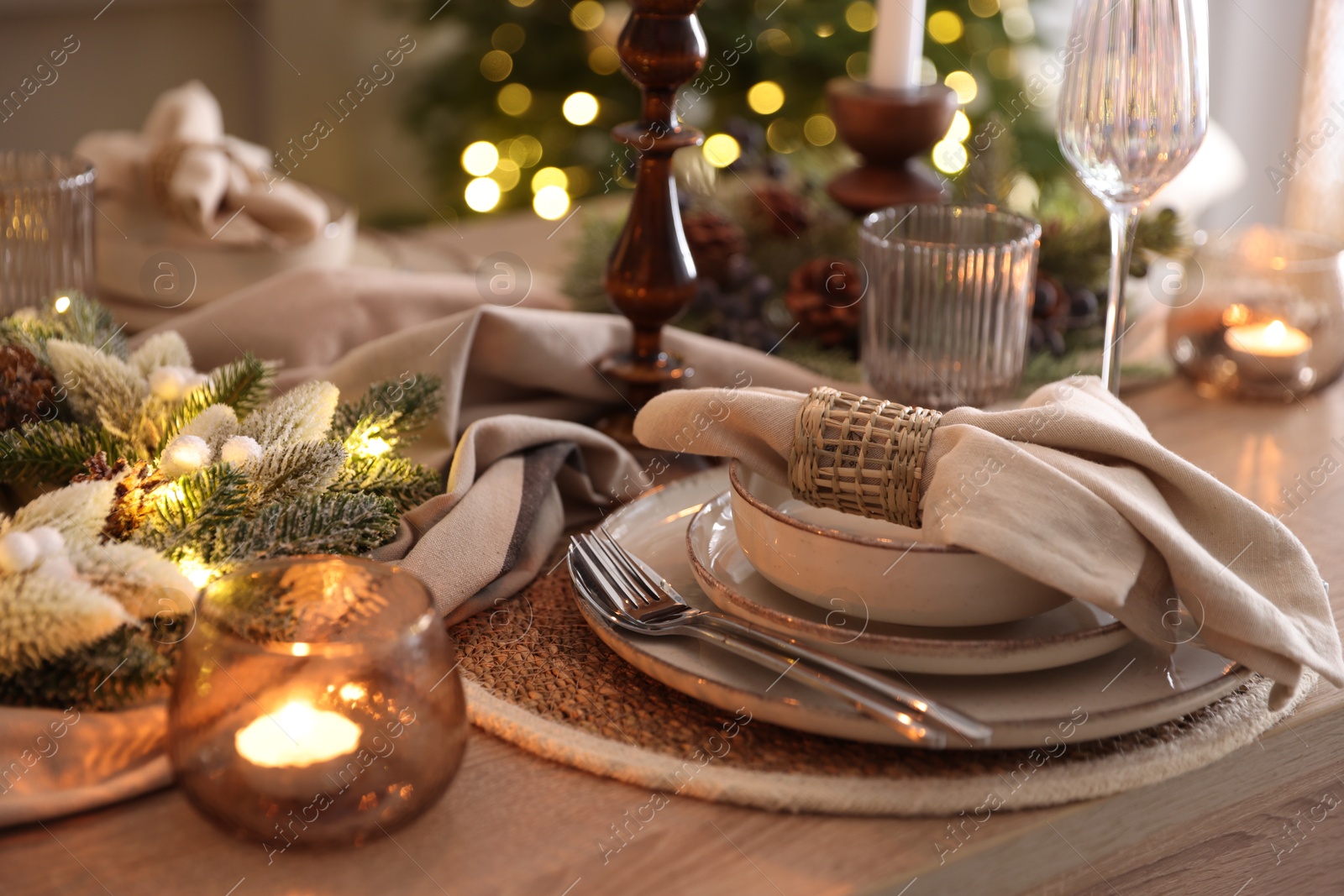 Photo of Christmas place setting with festive decor on wooden table in room, closeup