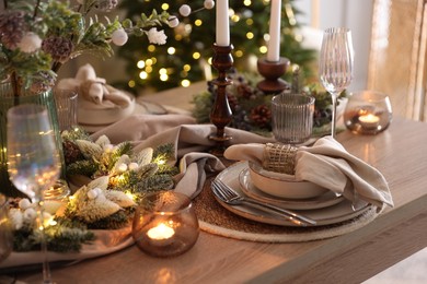 Photo of Christmas place setting with festive decor on wooden table in room