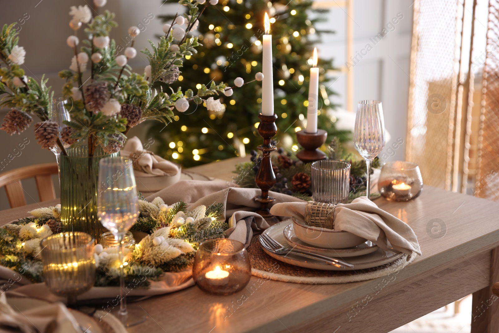 Photo of Christmas place setting with festive decor on wooden table in room