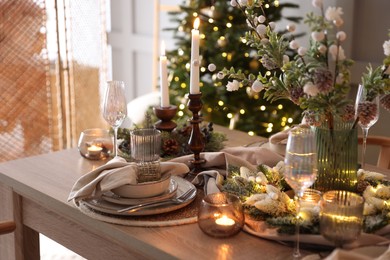 Photo of Christmas place setting with festive decor on wooden table in room