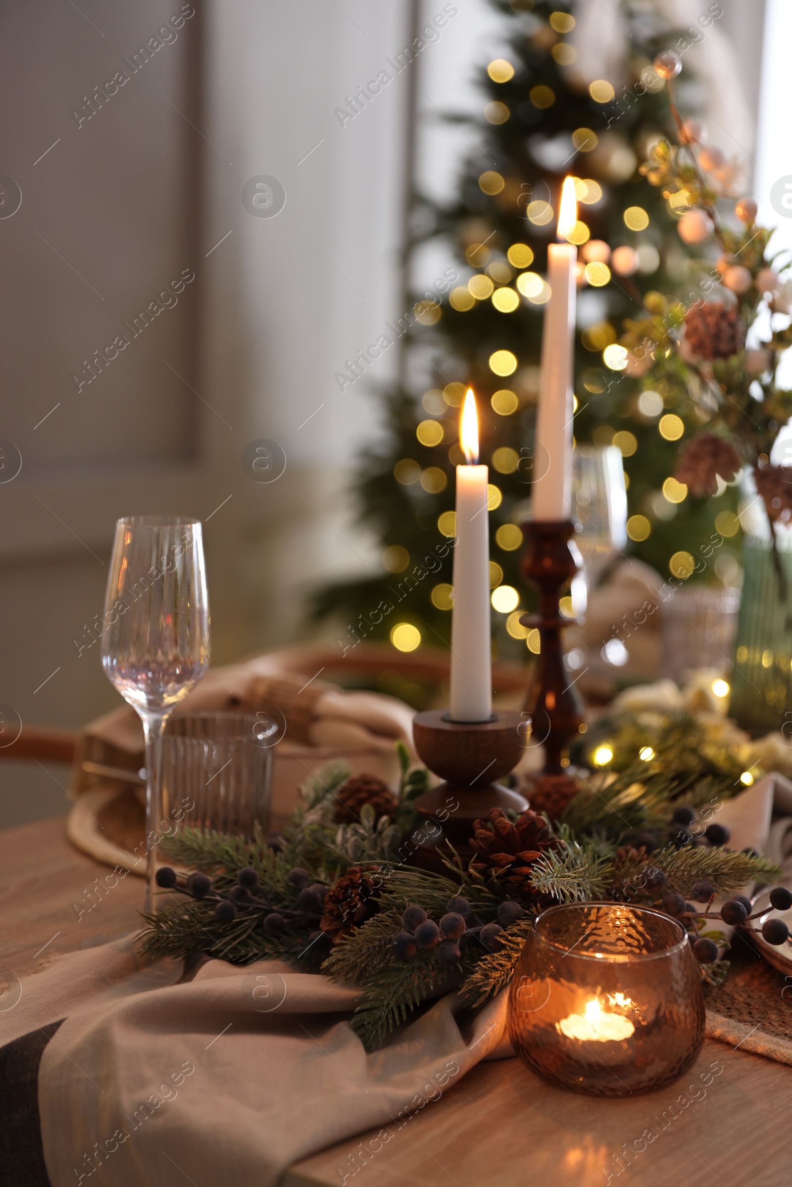 Photo of Christmas place setting with festive decor on wooden table in room