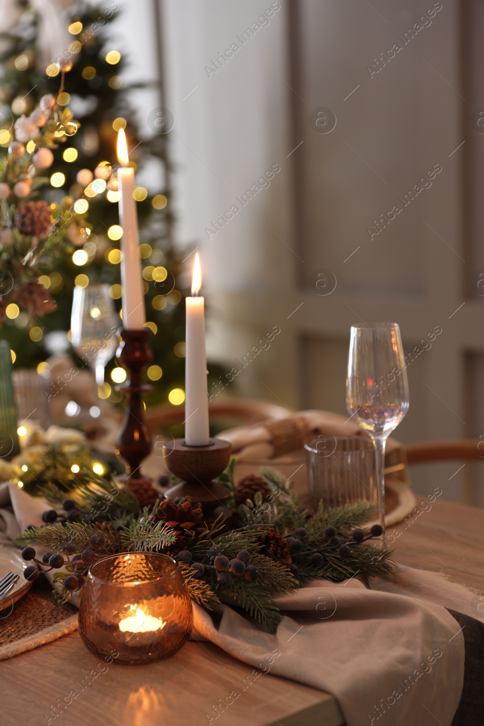 Photo of Christmas place setting with festive decor on wooden table in room