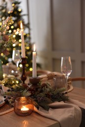 Photo of Christmas place setting with festive decor on wooden table in room