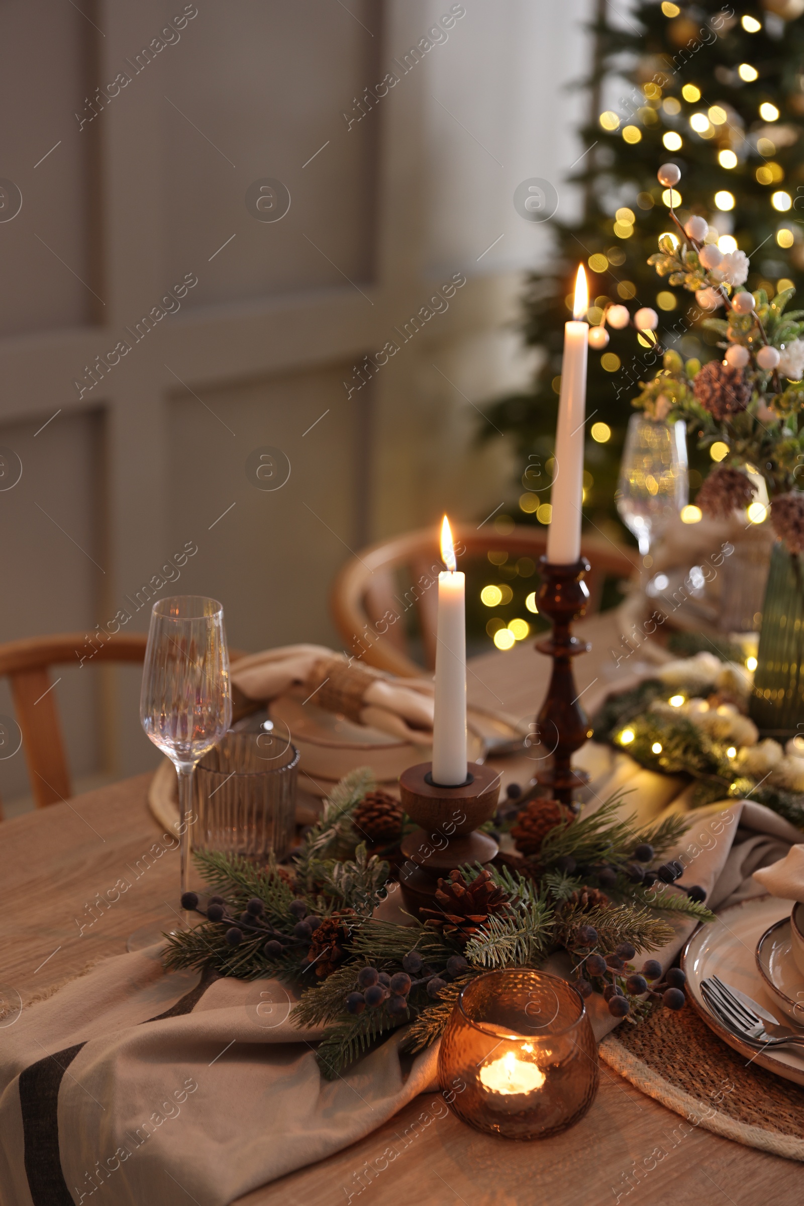 Photo of Christmas place setting with festive decor on wooden table in room