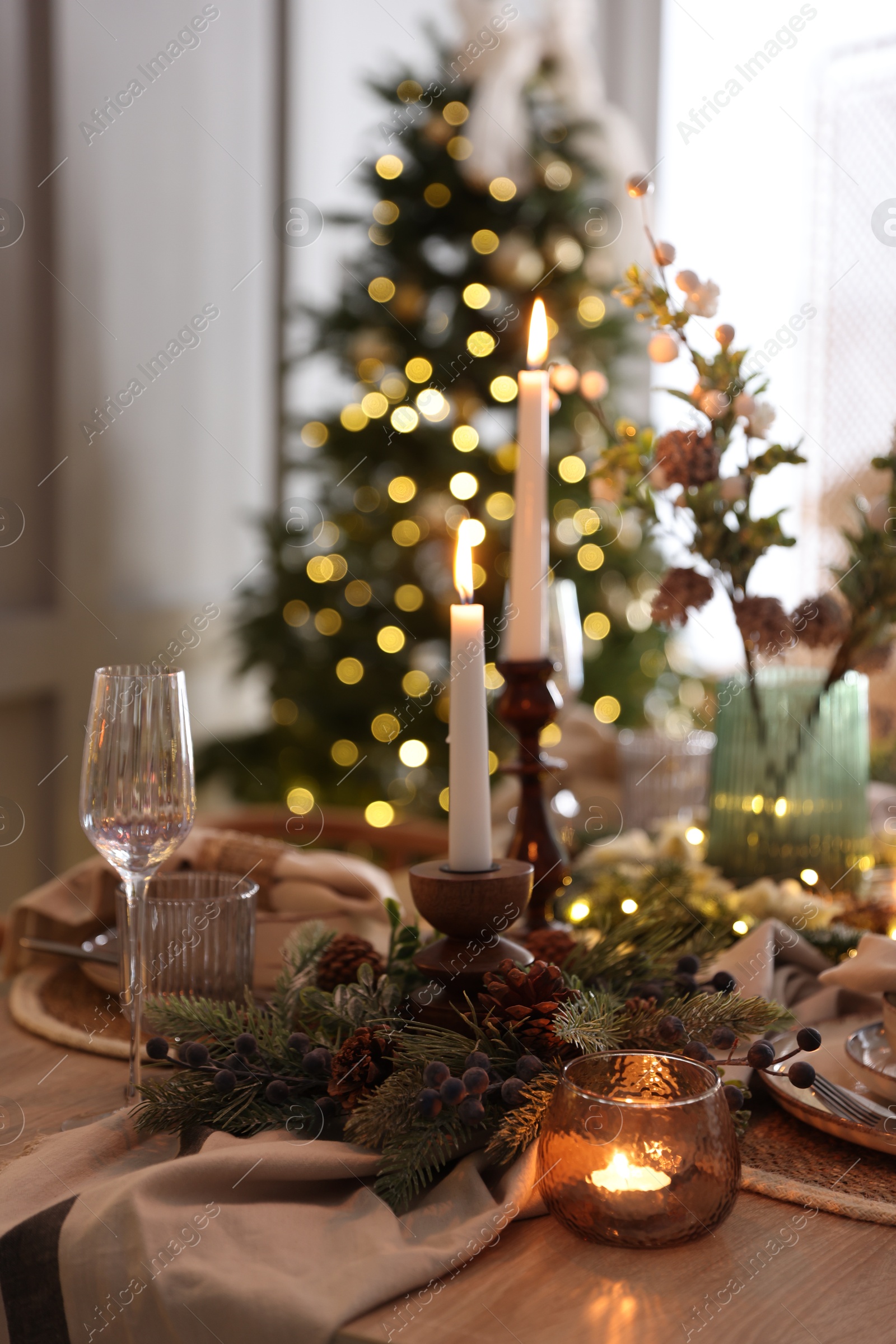 Photo of Christmas place setting with festive decor on wooden table in room