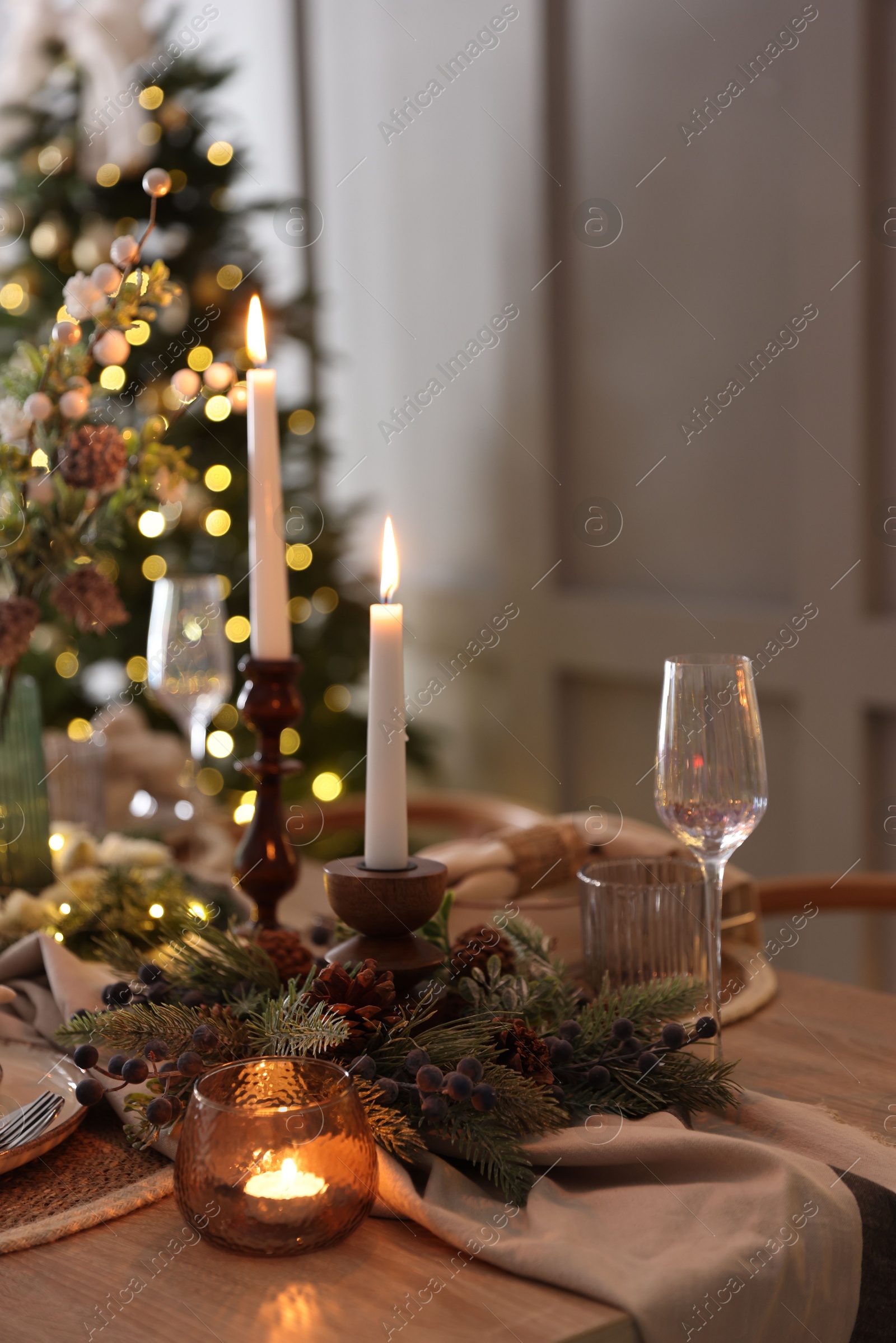 Photo of Christmas place setting with festive decor on wooden table in room