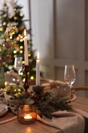 Photo of Christmas place setting with festive decor on wooden table in room