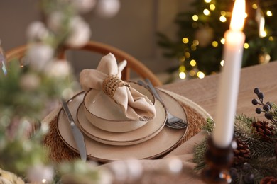 Photo of Christmas place setting with festive decor on wooden table in room