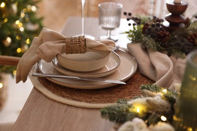 Photo of Christmas place setting with festive decor on wooden table in room, closeup