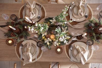 Photo of Christmas celebration. Festive table setting with dishware, glasses and decor in room, top view