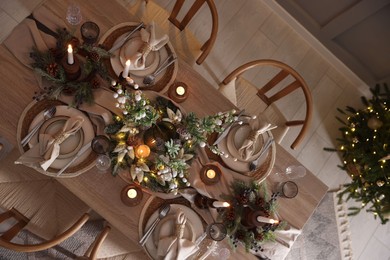 Photo of Christmas celebration. Festive table setting with dishware, glasses and decor in room, top view