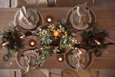 Photo of Christmas celebration. Festive table setting with dishware, glasses and decor in room, top view